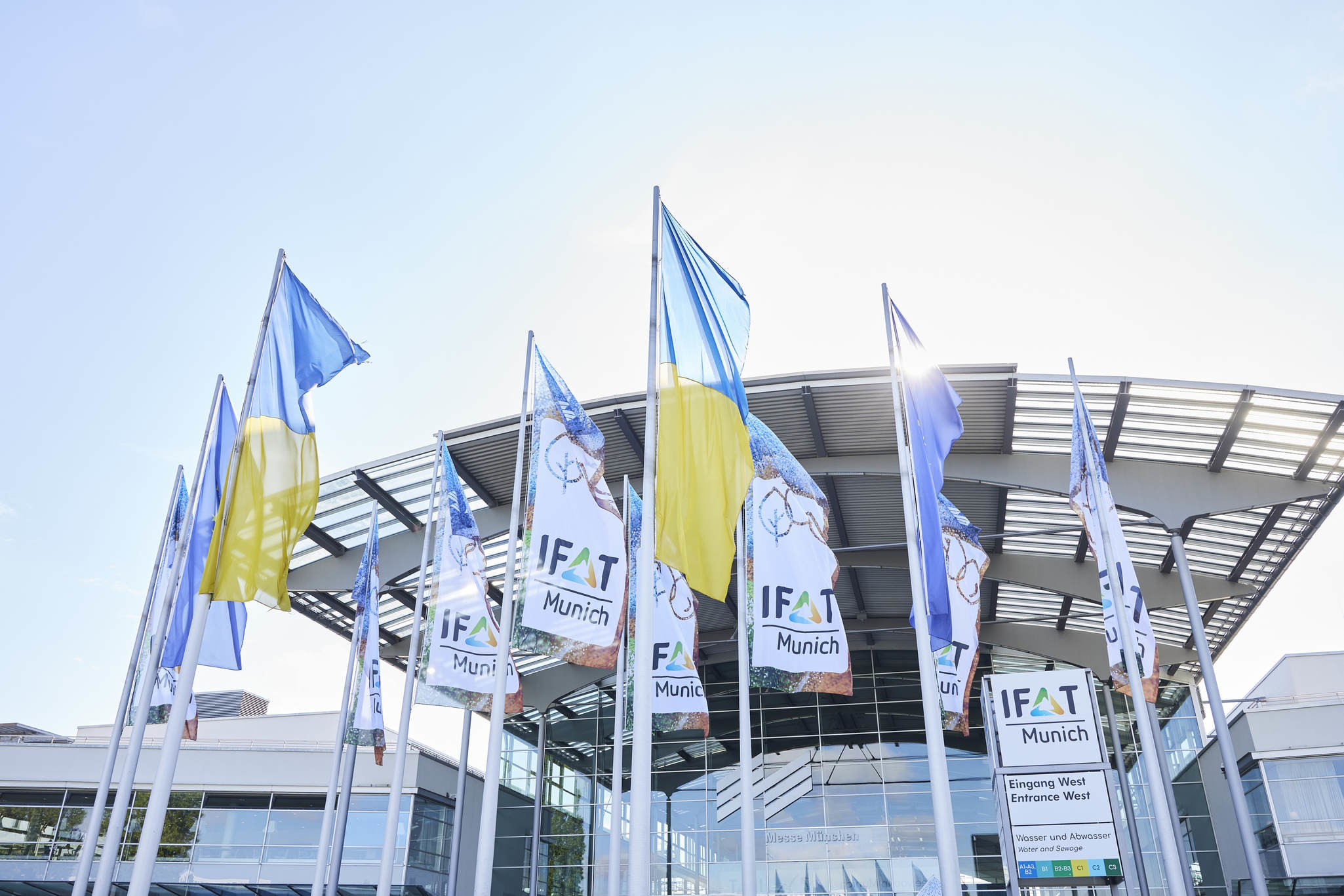 Frontansicht der Messe München, mit wehenden Flaggen mit IFAT Logo im Vordergrund
